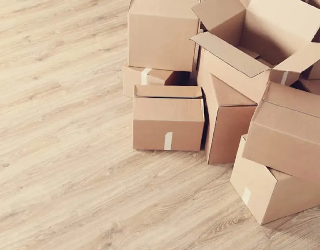 Mehrere geöffnete Umzugskartons stehen auf hellem Laminatboden. Symbolbild für Lieferung, Umzug, Möbeltransport und professionelle Services rund um Einrichtung und Wohnungswechsel.